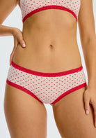 The Micro Hipster Panty in Hearts, which is an ivory low-rise panty with a red heart pattern and red lace trim.