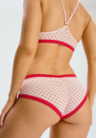 Back view of the Micro Hipster Panty in Hearts, which is an ivory low-rise panty with a red heart pattern and red lace trim.