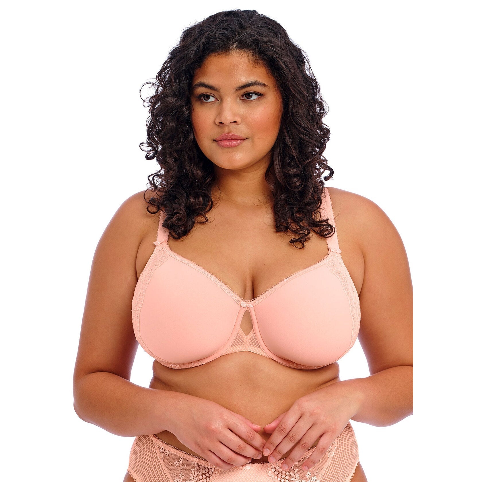 A women wearing a light link bra and panty set against a white back ground.