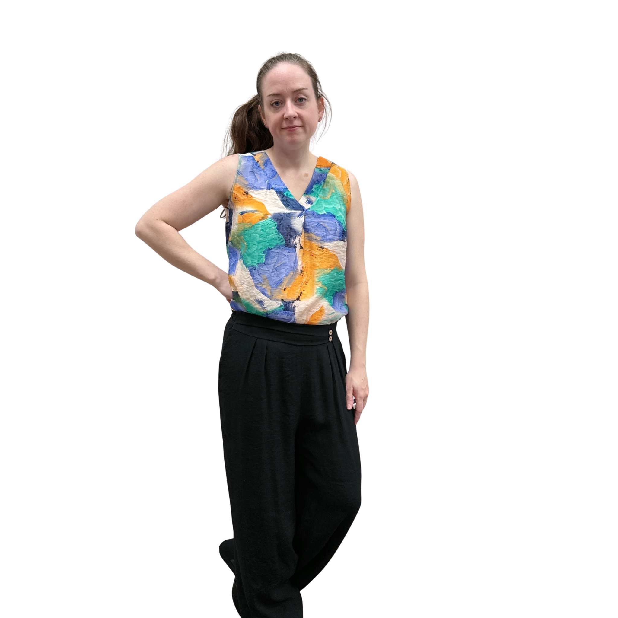 Woman wearing a colorful sleeveless top and black pants on a white background