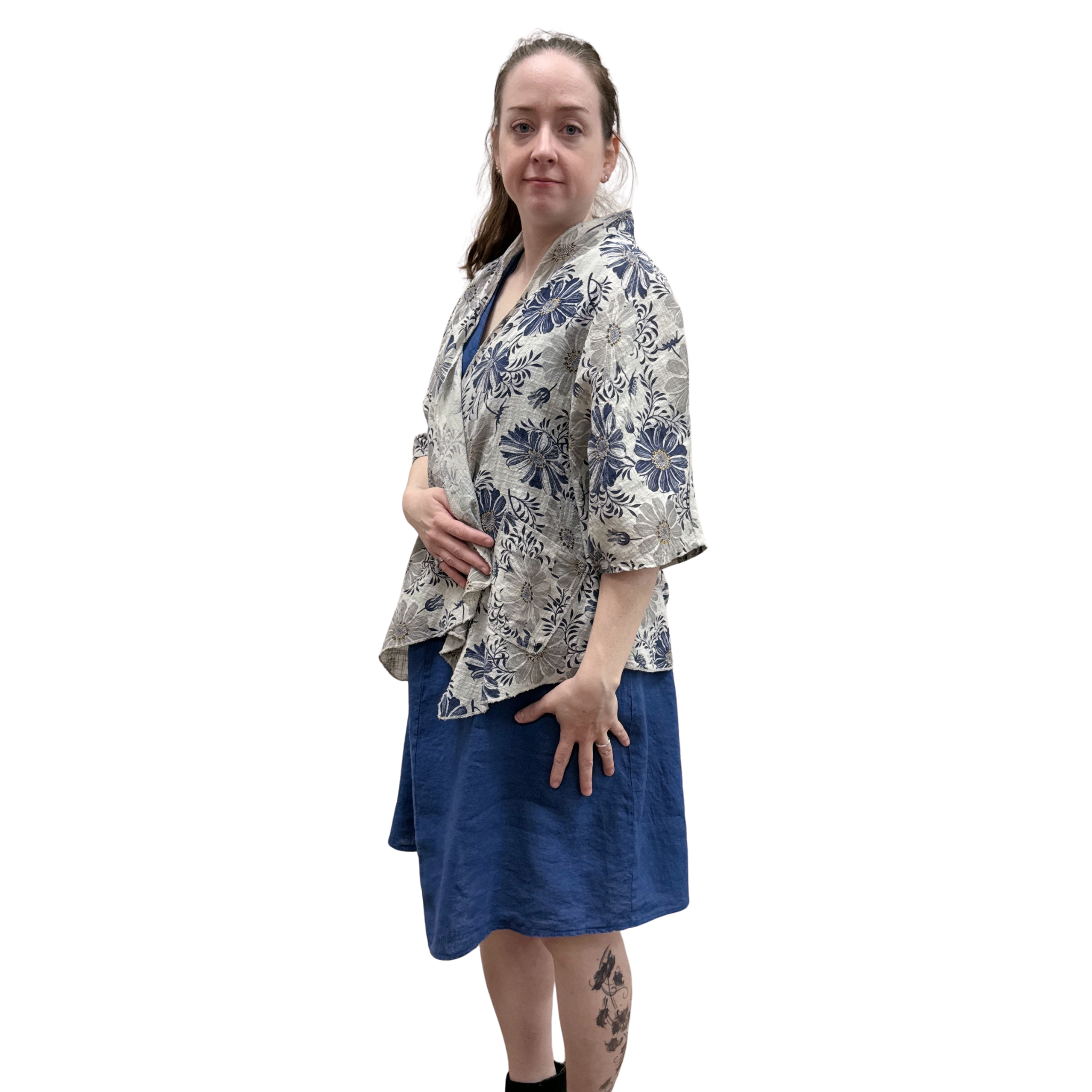 Woman wearing a floral kimono-style top and blue skirt on a white background