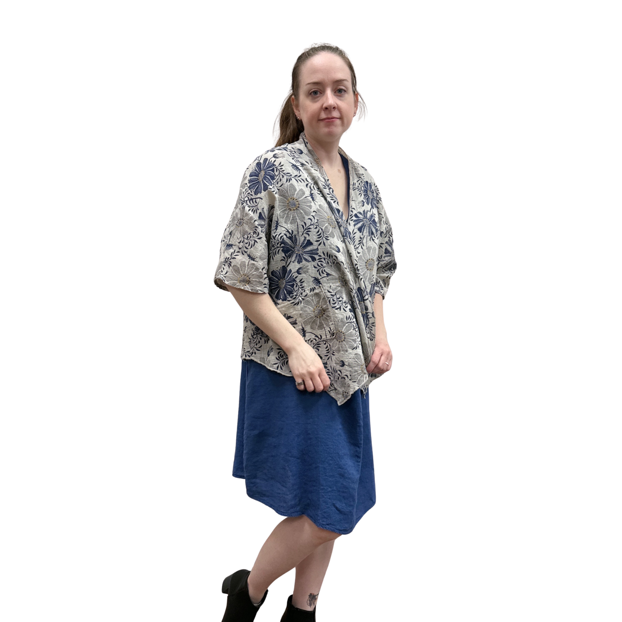 Woman wearing a floral kimono-style top and blue skirt on a white background