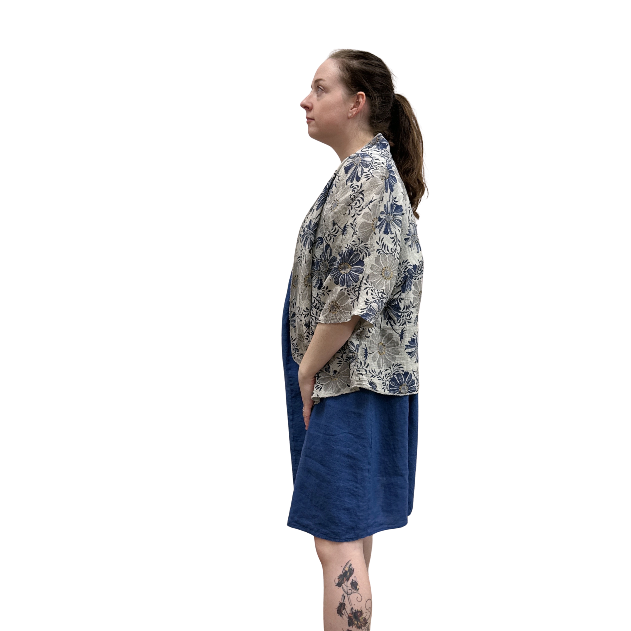 Woman wearing a floral kimono-style top and blue skirt on a white background