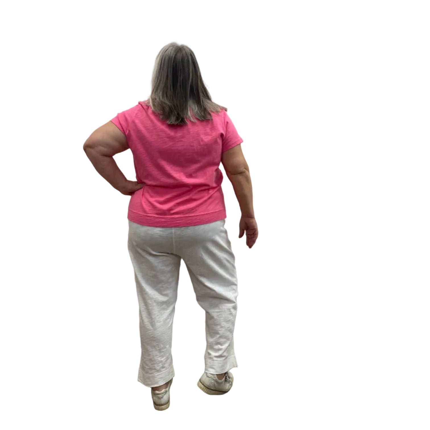 Woman wearing the Escape V Neck Tee in Cosmo Pink with a white heart shape on the front, paired with white pants, against a white background.
