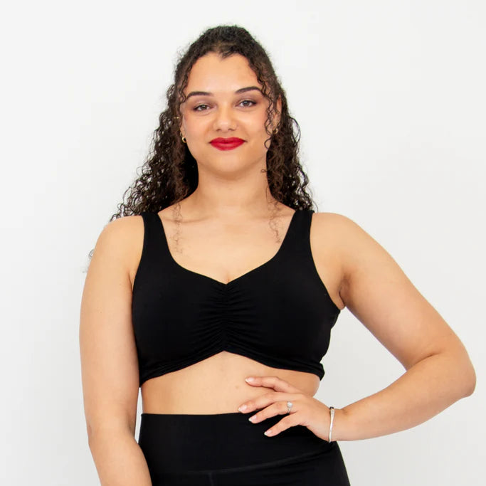 Woman wearing a black no wire bra and leggings on a white background