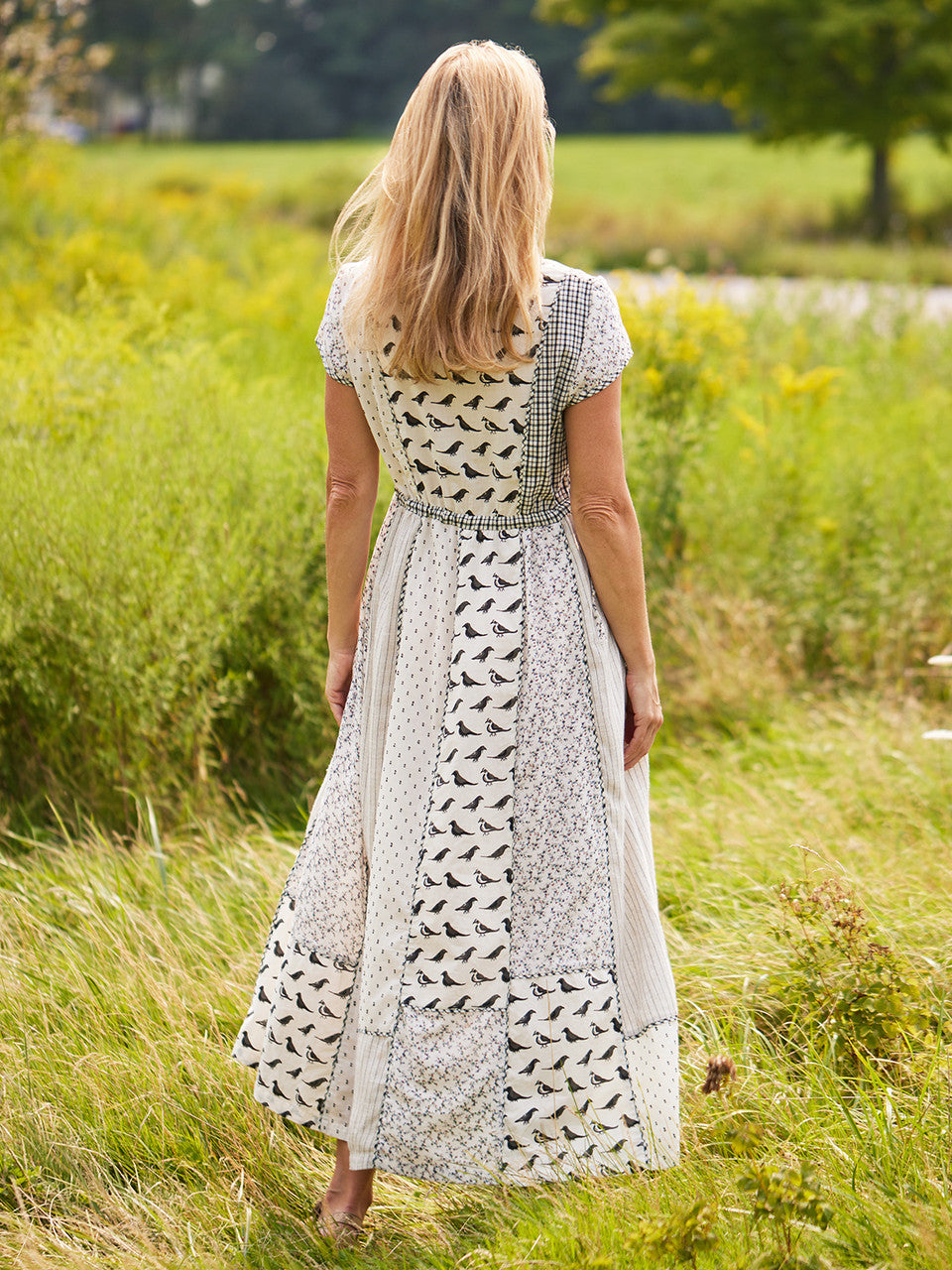 Woman in a patterned dress standing in a grassy field