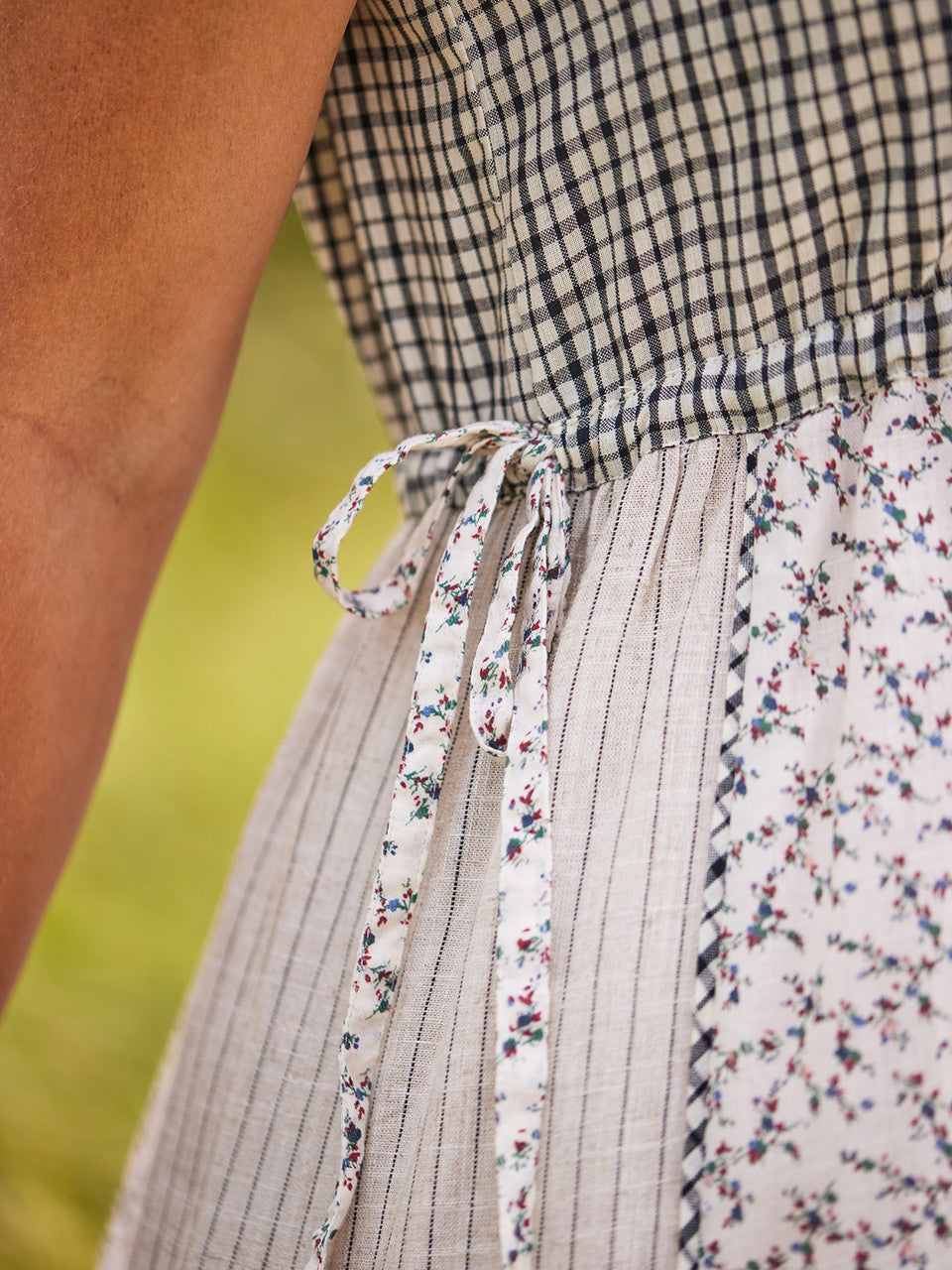 Close-up of a person wearing a patterned dress with floral trim.