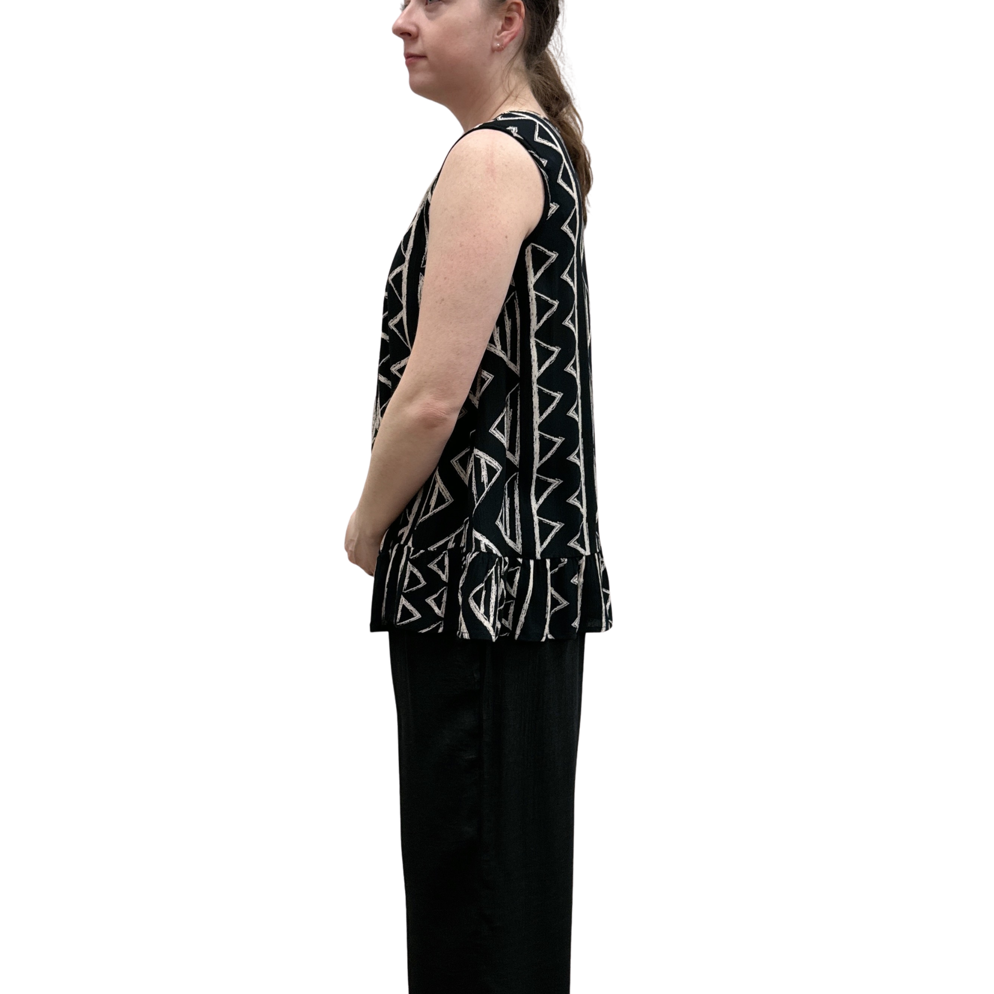 Woman wearing black with geometric print pattern sleeveless top with ruffle bottom on white background