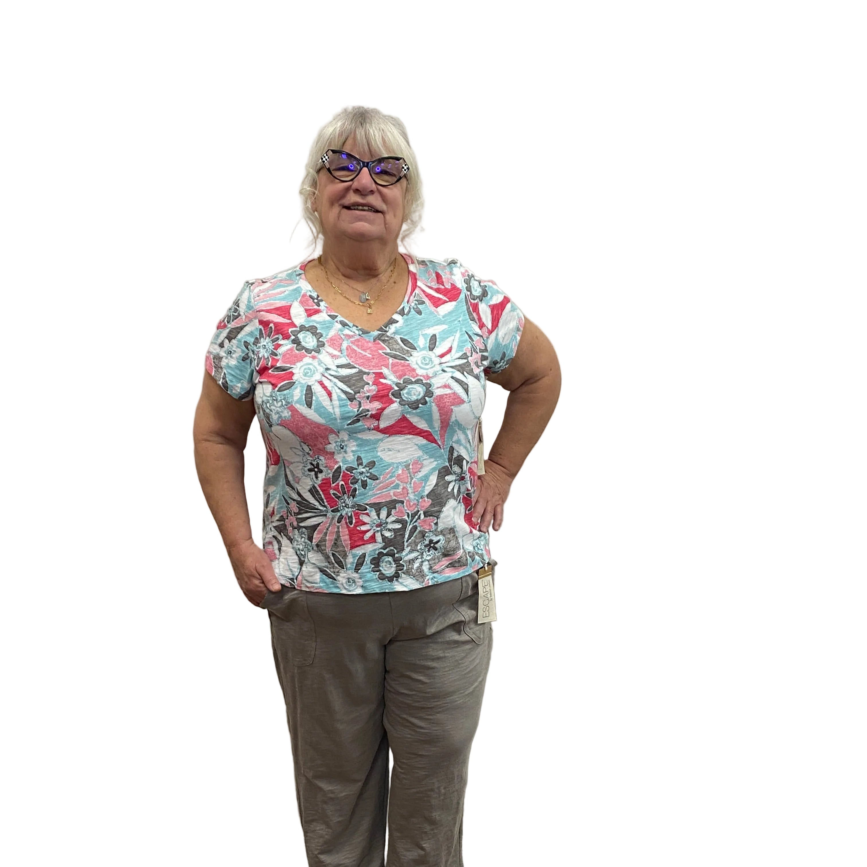 Woman wearing a pink and blue patterned Papa t-shirt with grey pants on white background.