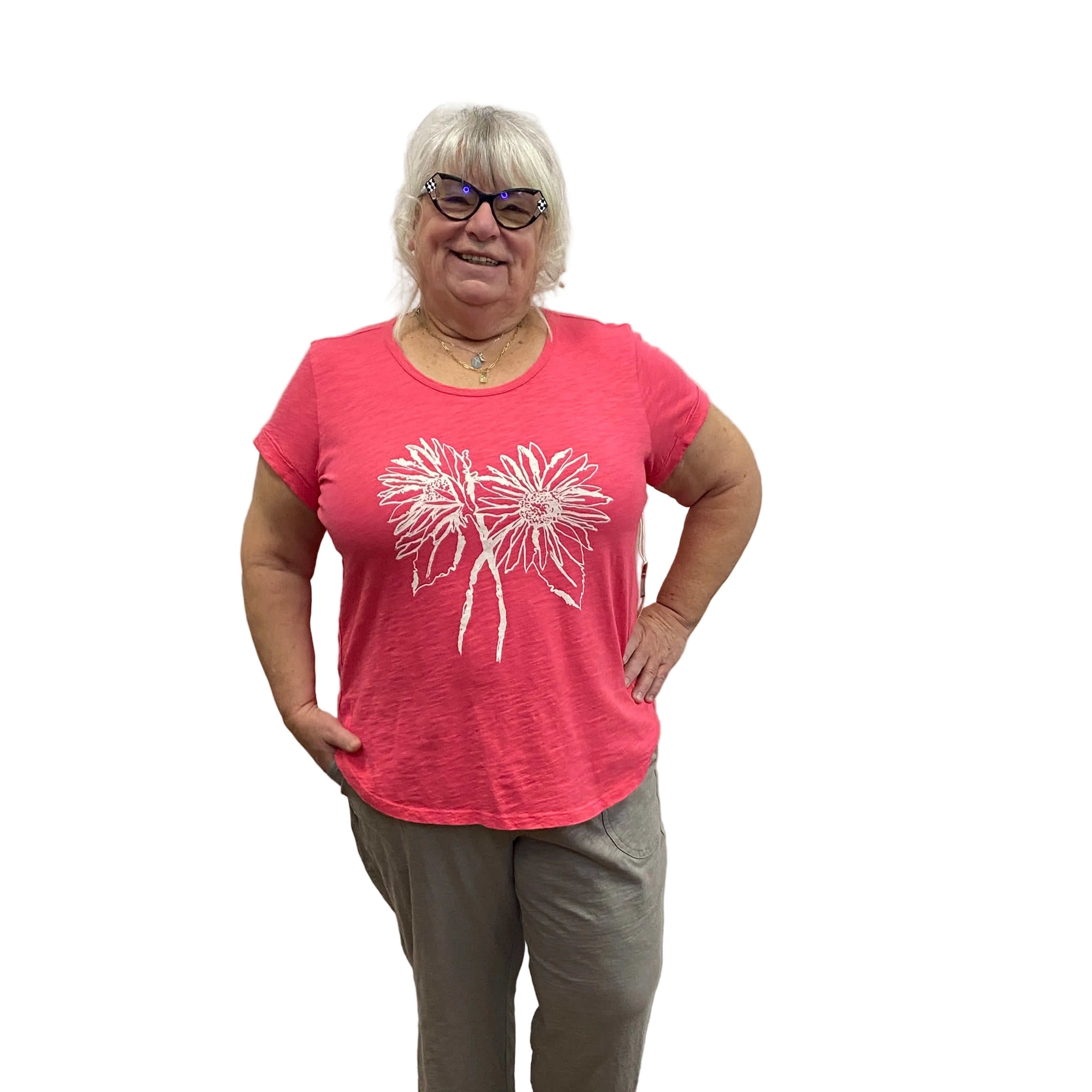 Person wearing a pink t-shirt with a white floral design, standing indoors on a wooden floor.