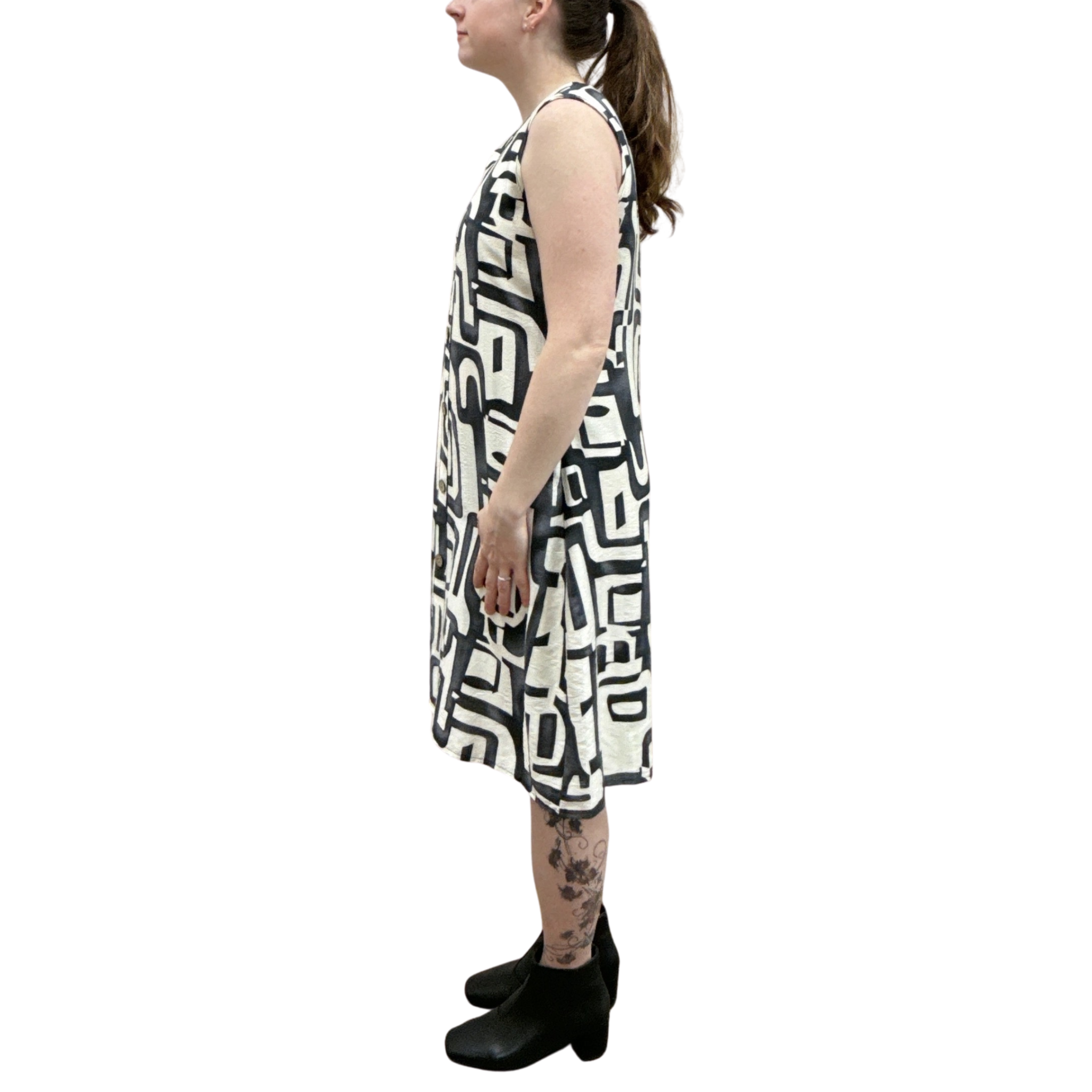 Person wearing a sleeveless dress with a black and white geometric pattern on a white background