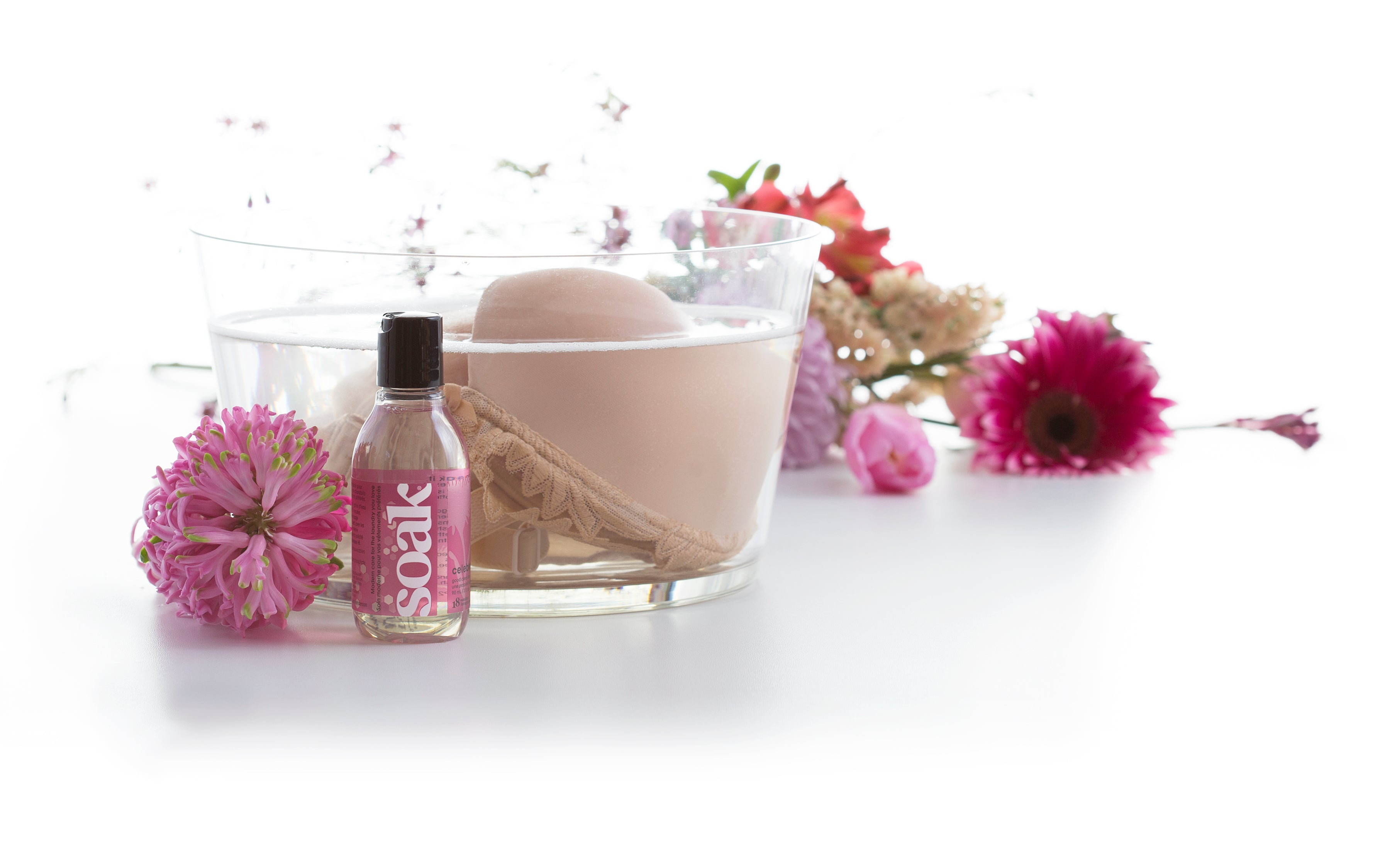 Soak 3oz Celebration bottle shown with an example of soaking a bra to wash your delicates.