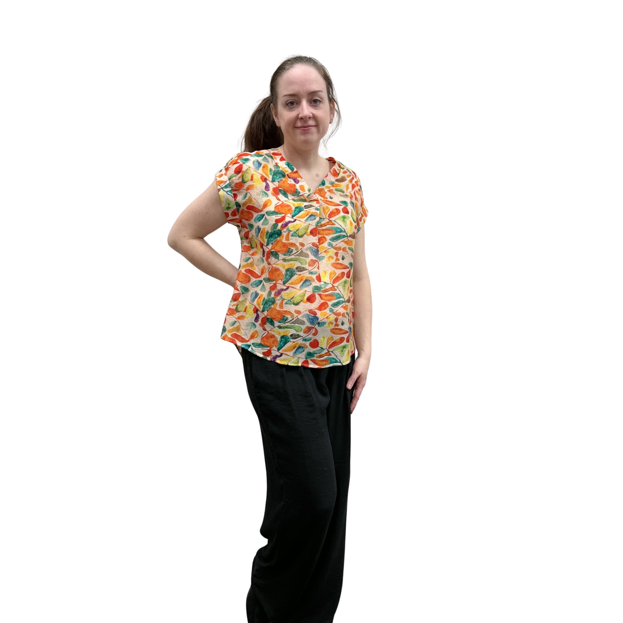 Woman wearing a colorful patterned shirt and black pants on a white background