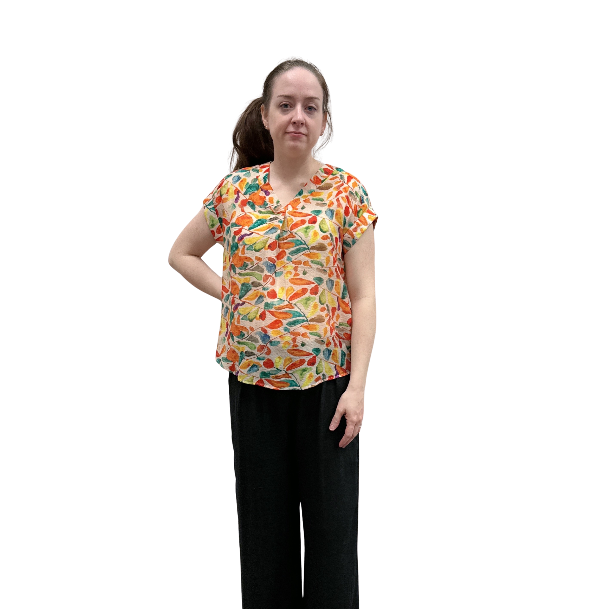 Woman wearing a colorful patterned shirt and black pants on a white background