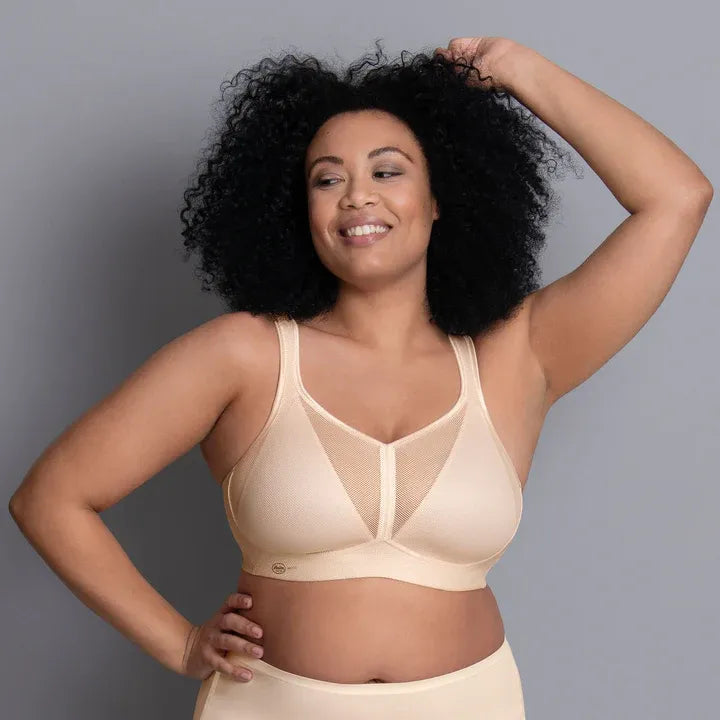 Woman wearing a beige bra and underwear set against a gray background