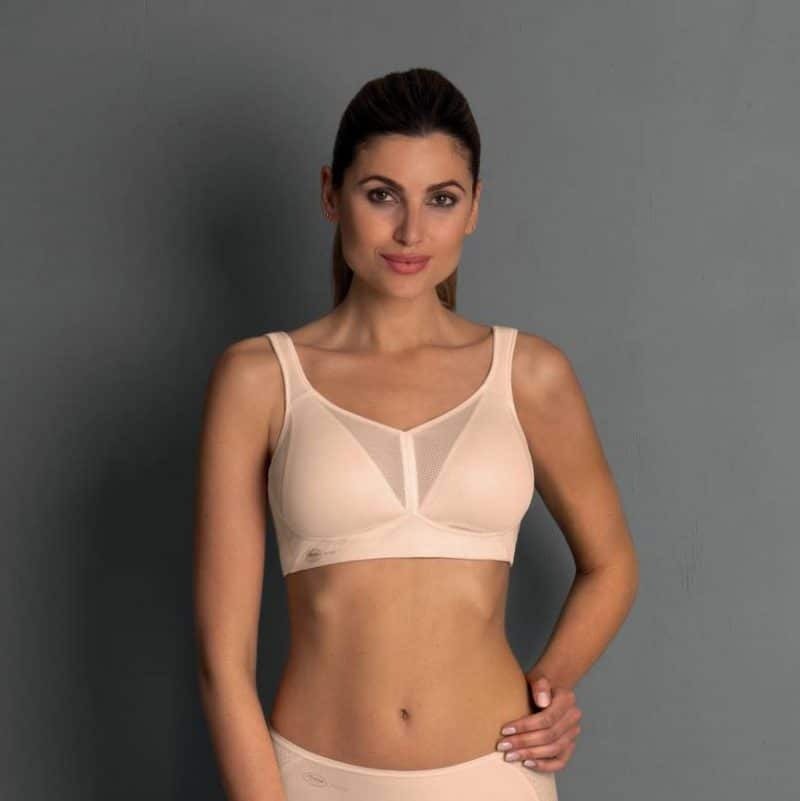 Woman wearing a beige bra against a gray background