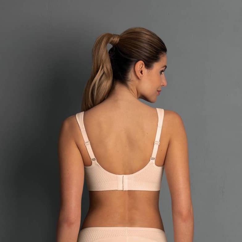 Woman wearing a beige bra against a gray background