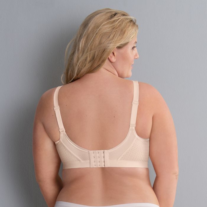 Woman wearing a beige bra against a gray background
