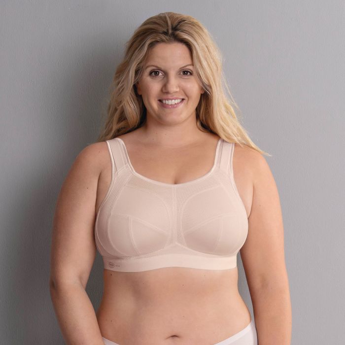 Woman wearing a beige bra against a gray background