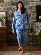 A woman wearing a blue pajama set against a grey wall.