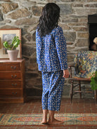 A woman wearing a blue pajama set against a grey wall.