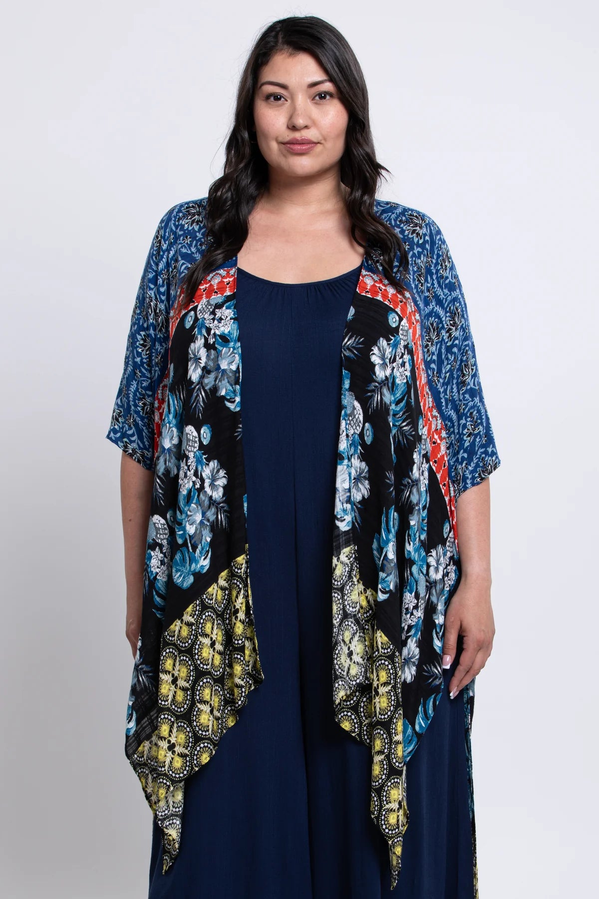 Woman wearing a floral kimono over a navy dress on a white background