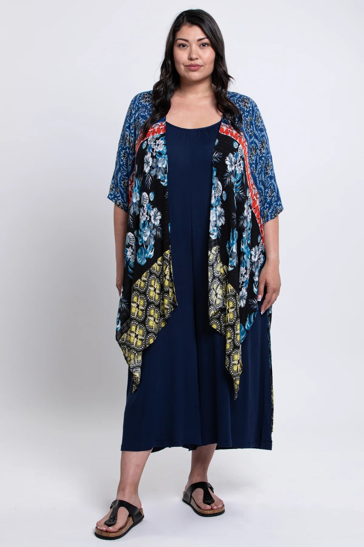 Woman wearing a navy dress with a floral kimono over it on a white background