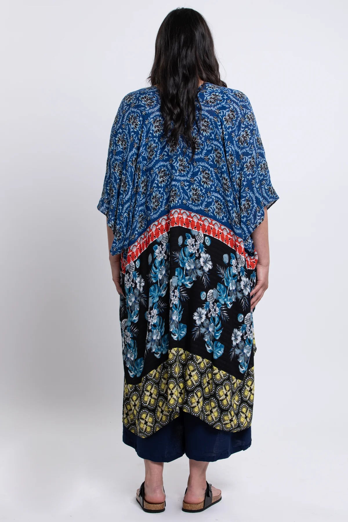 Person wearing a colorful floral dress with a patterned overlay on a white background