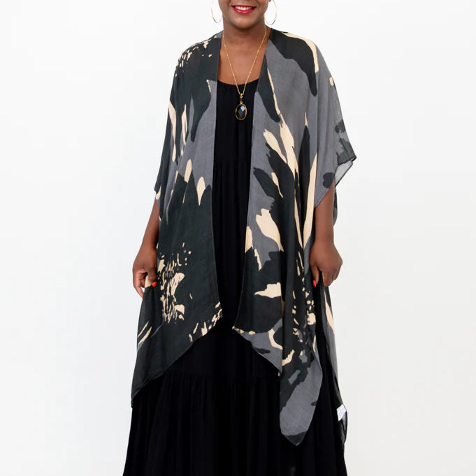 Woman wearing a long, patterned kimono over a black dress on a white background