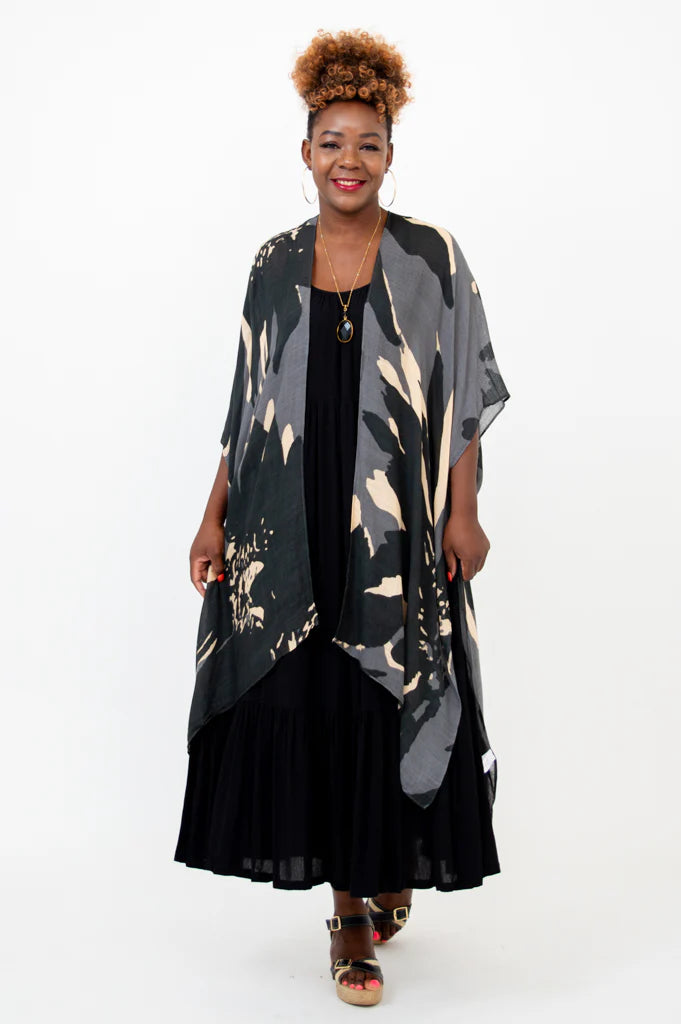Woman wearing a long, patterned kimono over a black dress on a white background