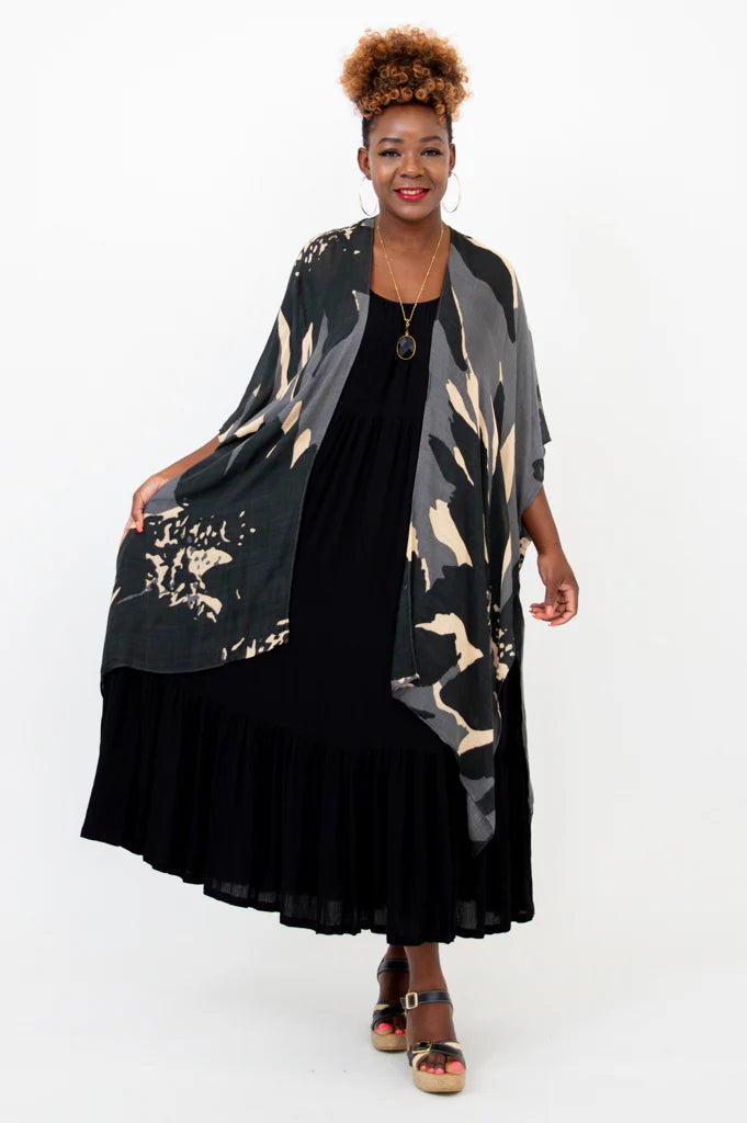Woman wearing a black and beige patterned kimono over a black dress on a white background