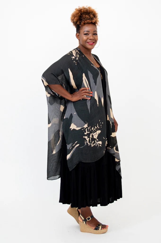 Woman wearing a black and gold patterned kimono over a black dress on a white background