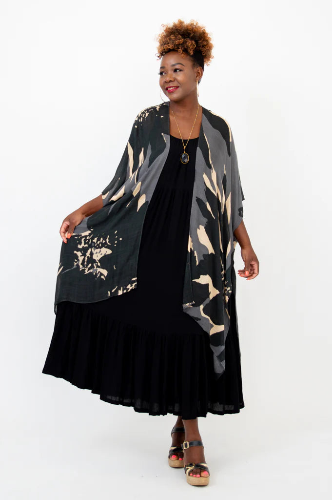 Woman wearing a black dress with a floral kimono over it on a white background
