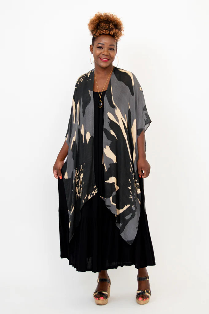 Woman wearing a black and beige patterned kimono over a black dress on a white background