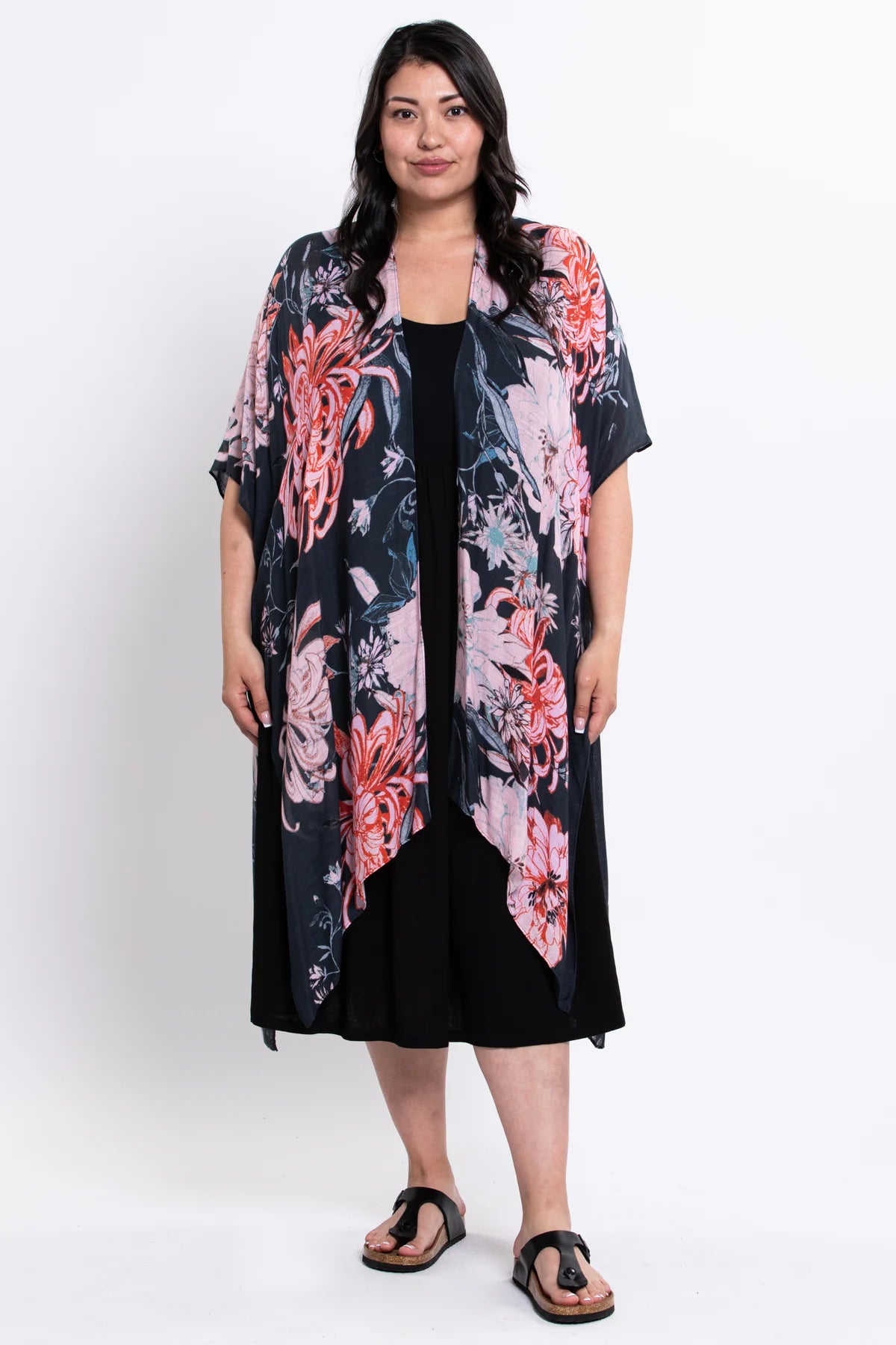 Woman wearing a floral kimono over a black dress on a white background