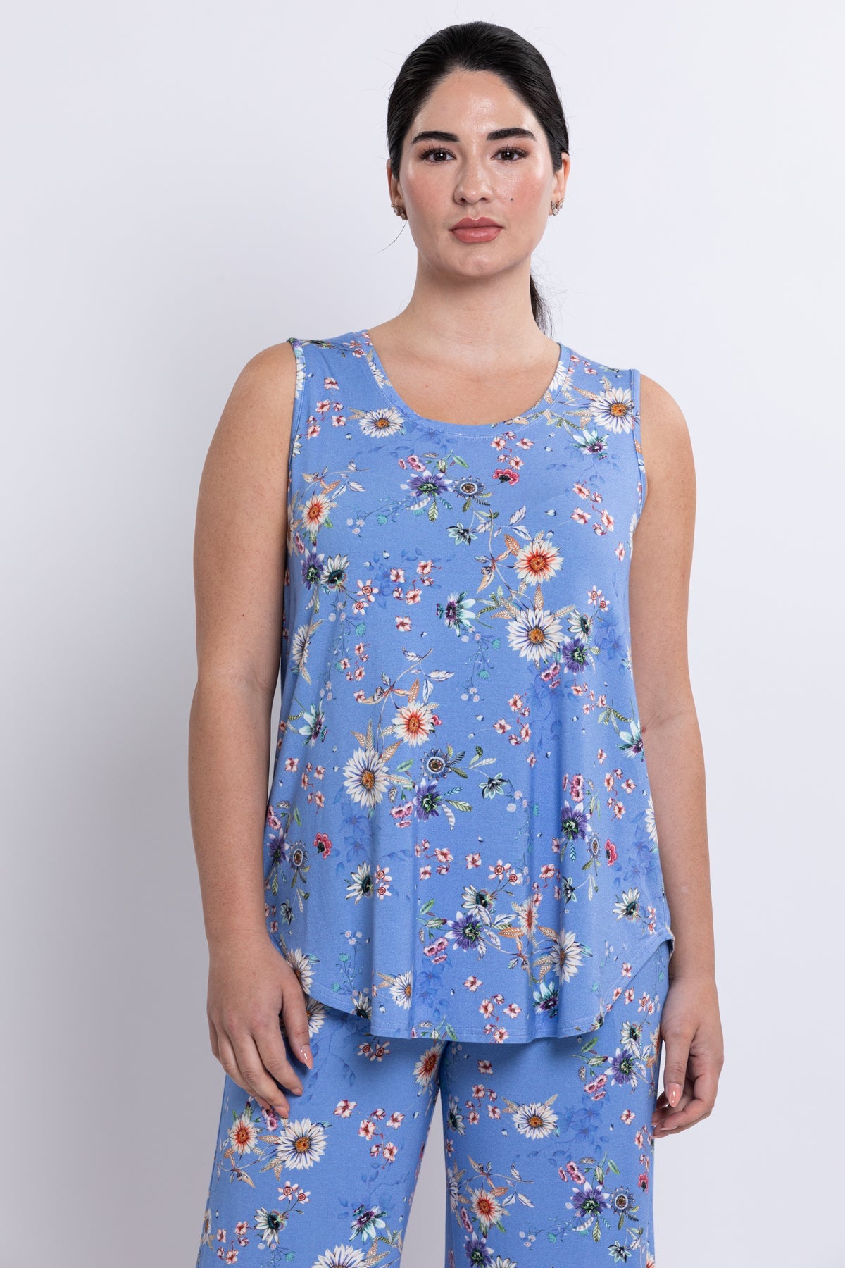 Woman wearing a blue floral sleeveless top and pants on a white background