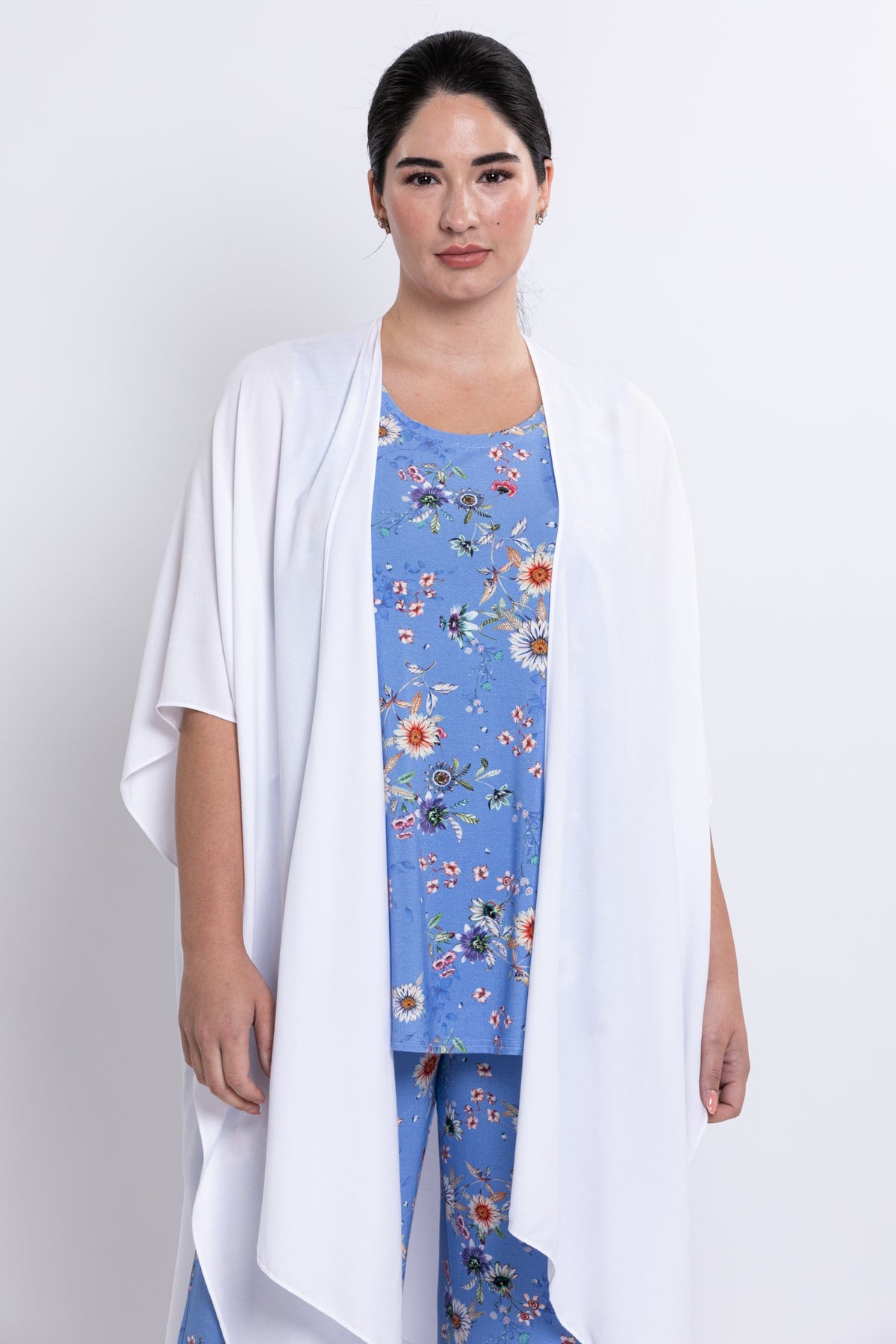 Woman wearing a blue floral outfit with a white cardigan on a white background