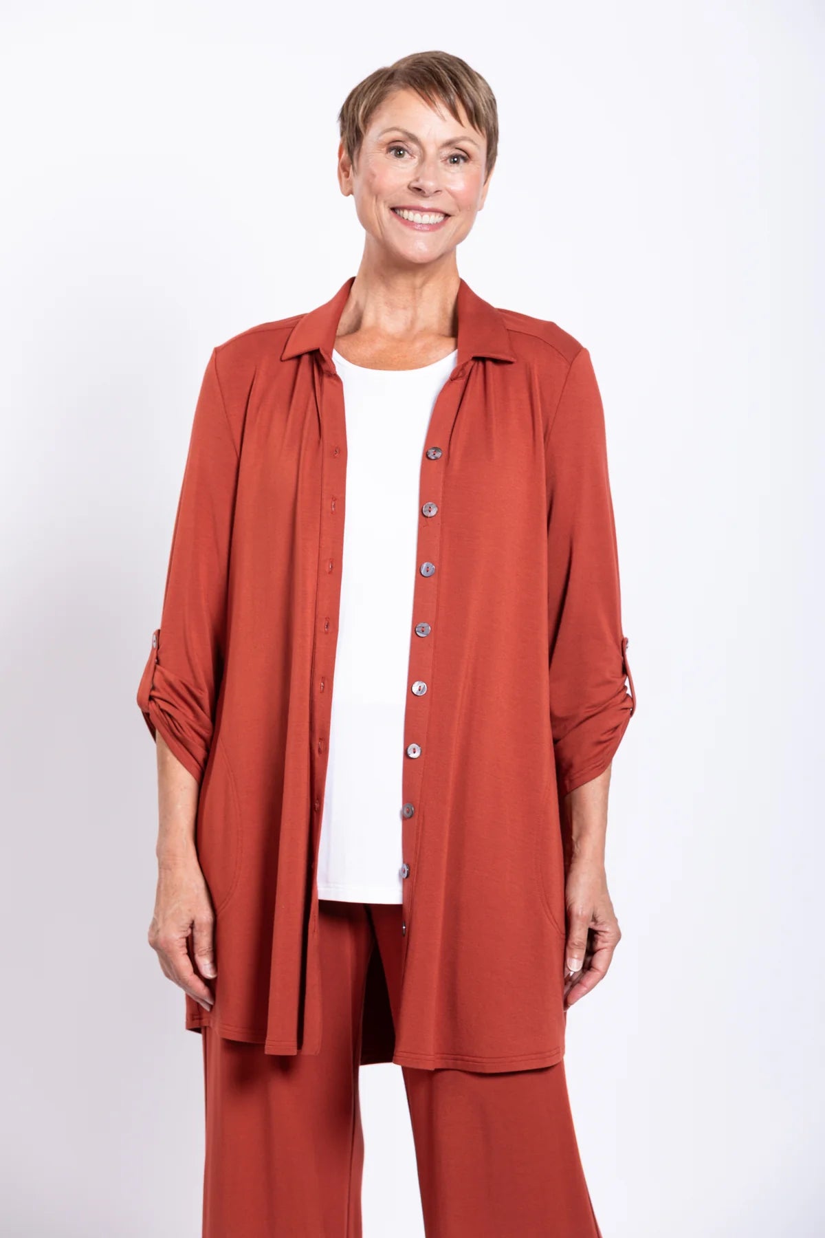 Woman wearing a rust-colored outfit with a matching jacket and pants on a white background