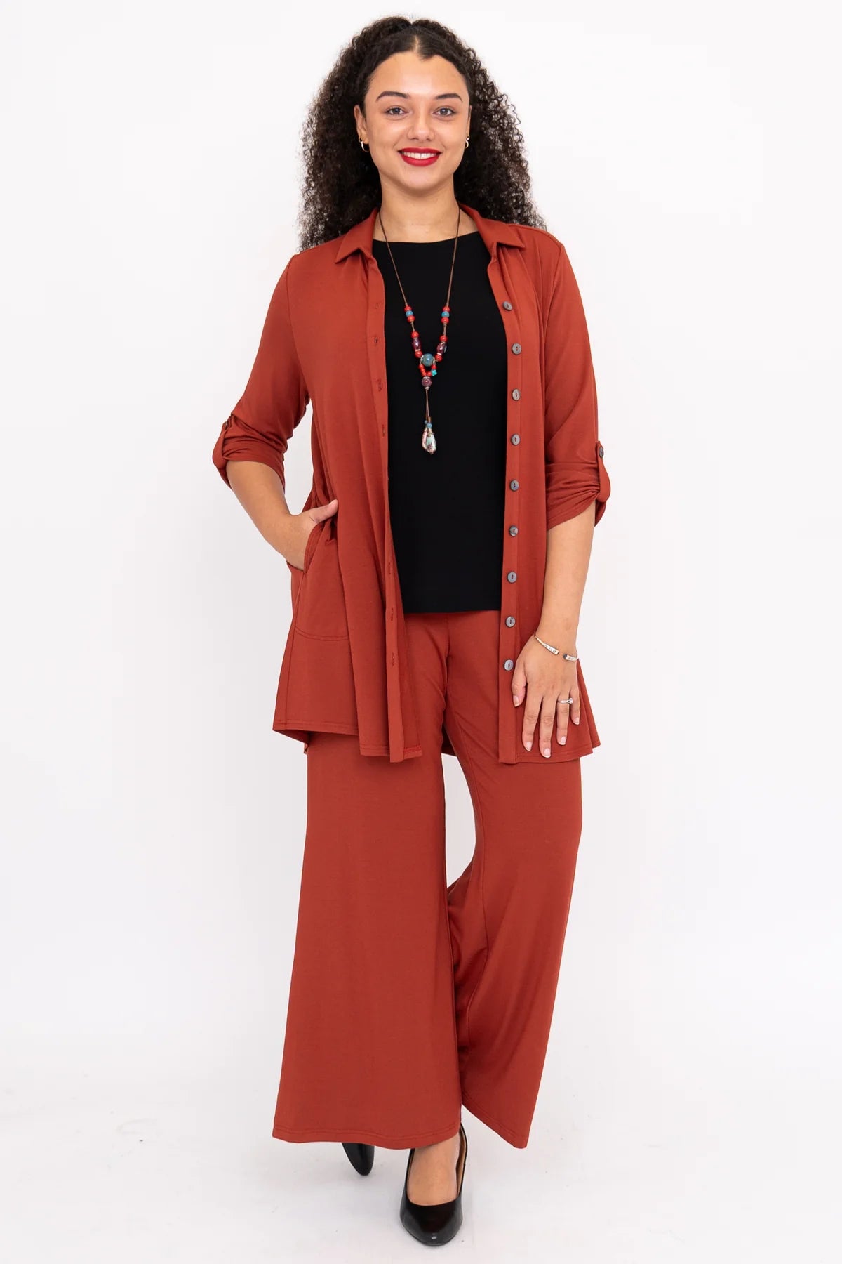 Woman wearing a rust-colored outfit with a black top on a white background