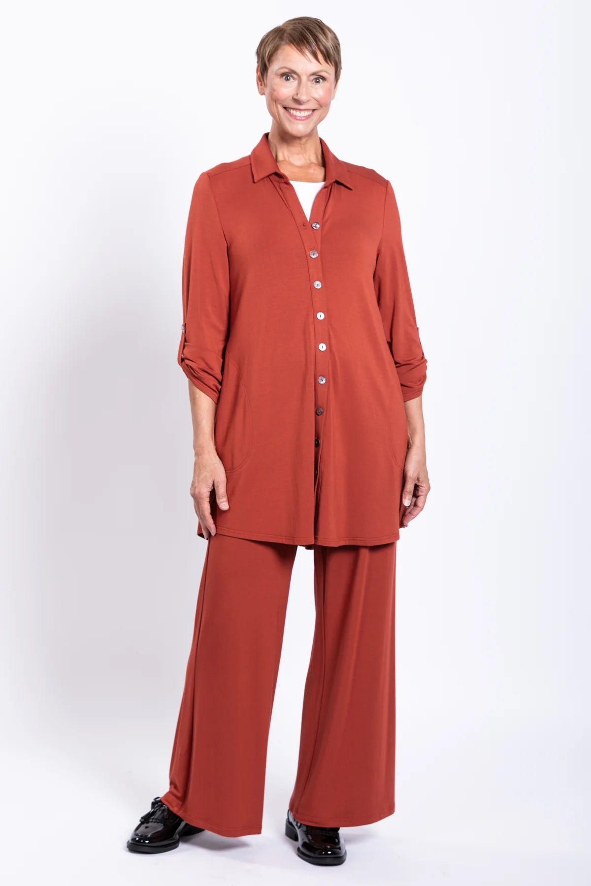 Woman wearing a rust-colored outfit with wide-leg pants on a white background