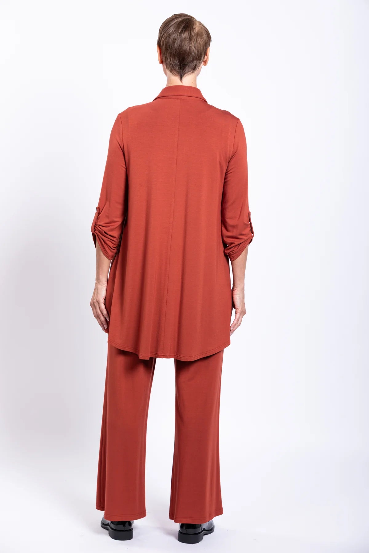 Person wearing a rust-colored outfit on a white background