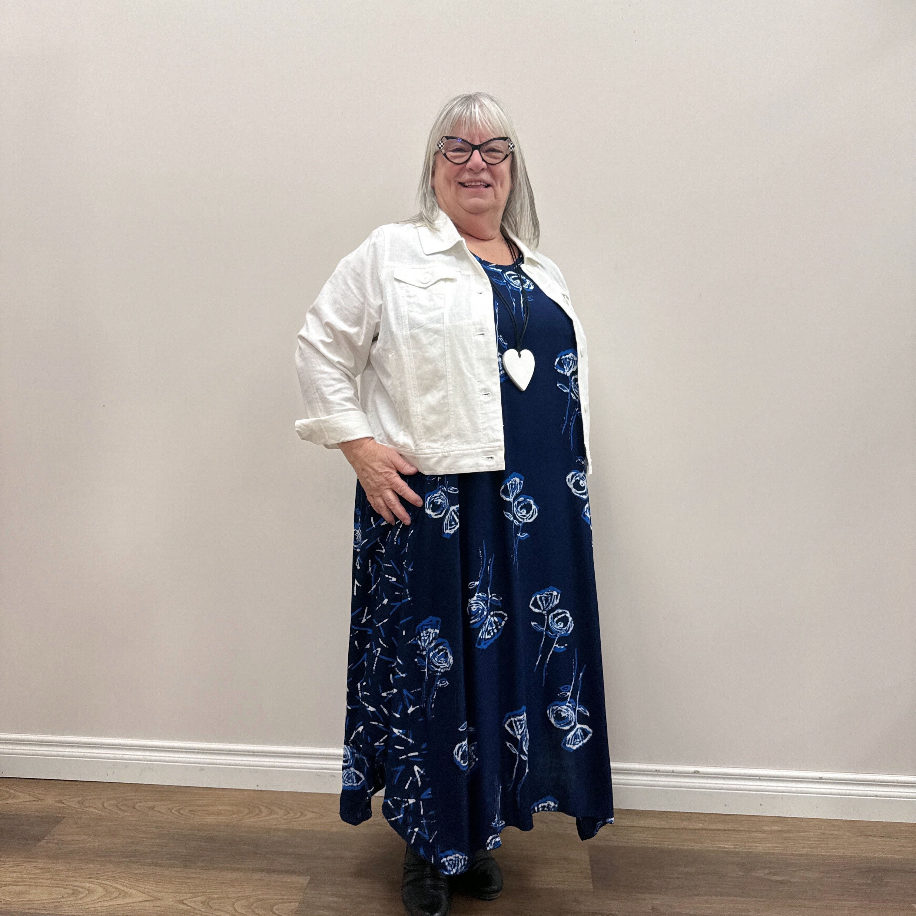Woman wearing a white Blue Sky Colleen Jacket over a navy dress on white background.