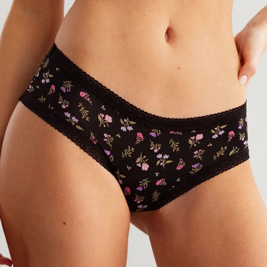 Close up of The Micro Hipster in Liberty floral print, black panty with pink and purple flowers, shown on a model.