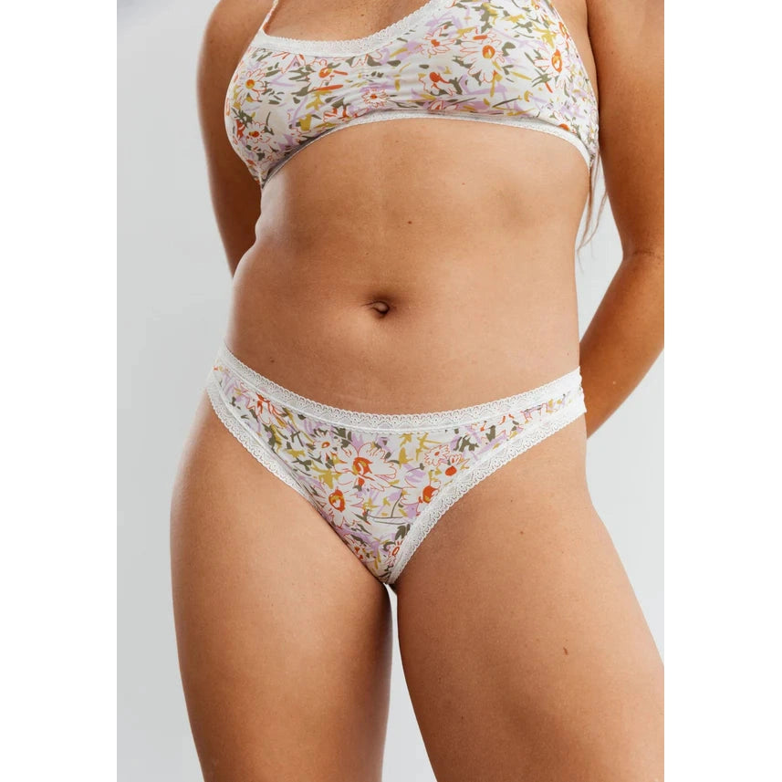 The Micro Thong in Botanic, white panty with floral pattern, shown on a model to show the front view.