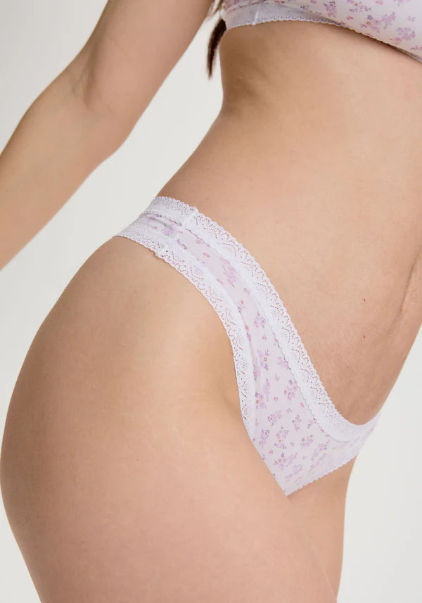 White lace thong worn by a person on a light gray background