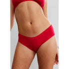 This image features a vibrant red microfiber hipster panty, designed for comfort and a second-skin feel. The panty, presented in a striking lipstick box, boasts a low-rise cut that enhances its playful and cheeky appeal.