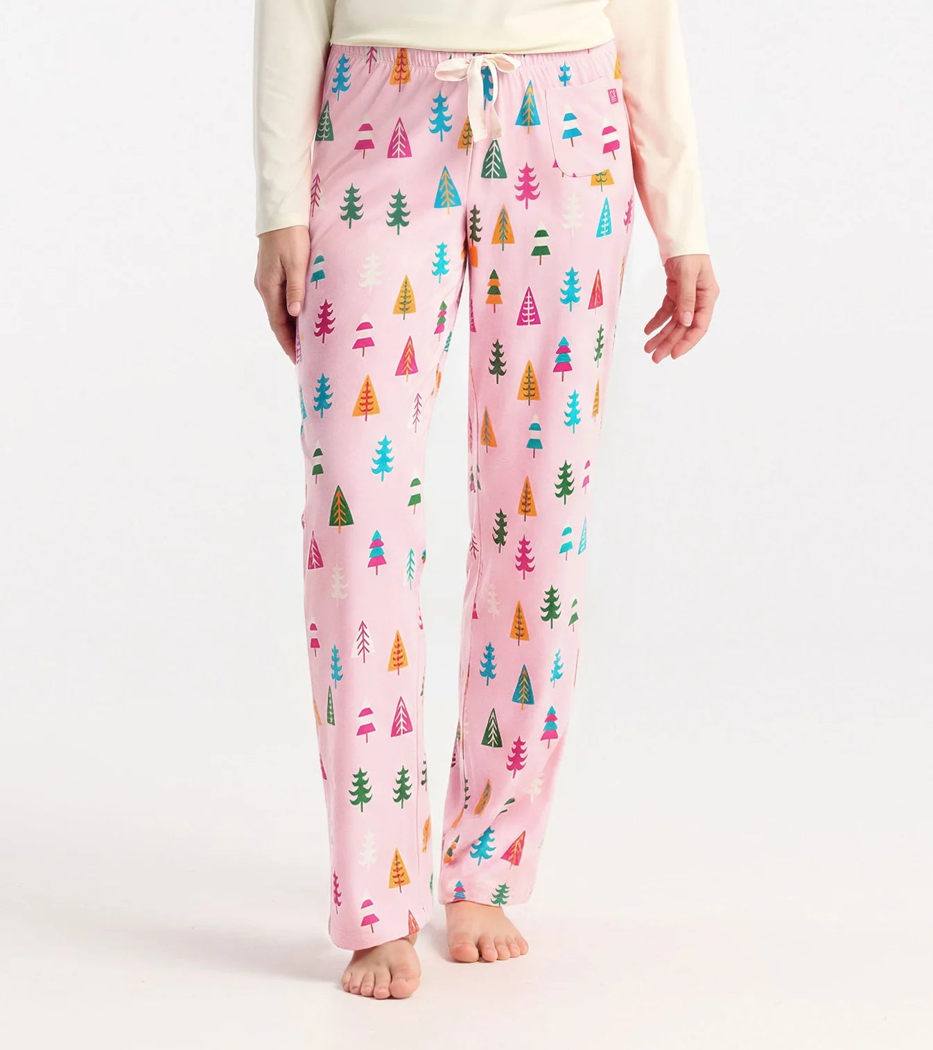 Pink pajama pants with colorful tree pattern worn by a person on a white background