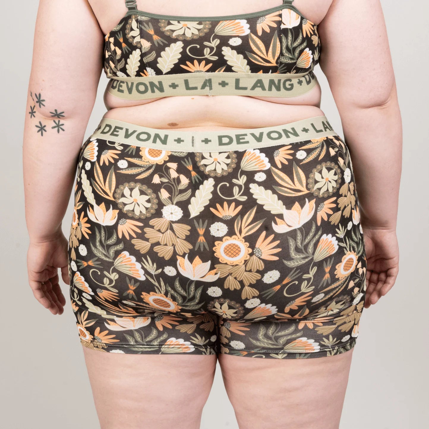 Person wearing a floral patterned underwear set with 'Devon + Lang' branding on a plain background