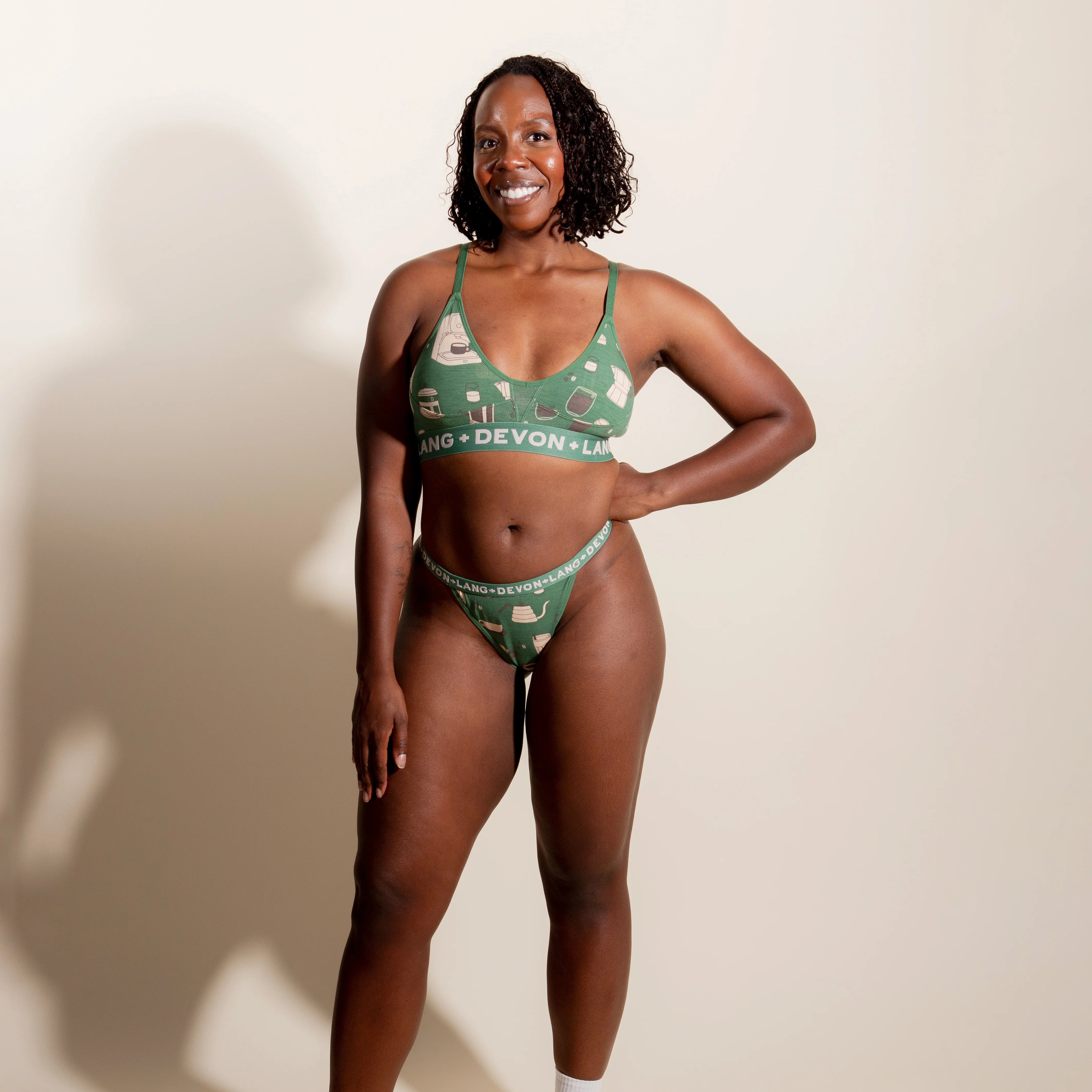Woman wearing a green patterned underwear set against a plain background