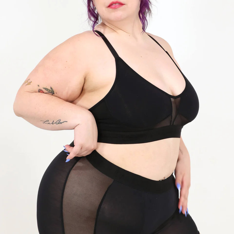 A woman wearing a black bra and shorts set on a white background